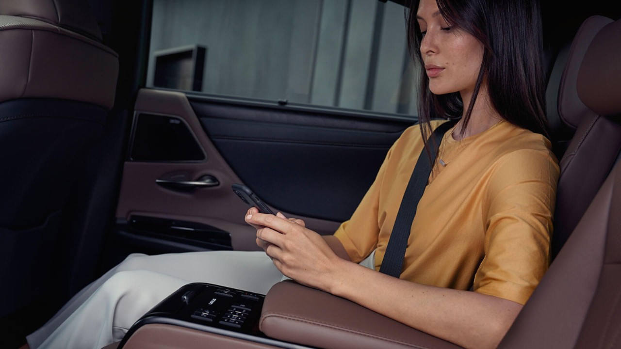 A woman on her phone sat in the rear passenger seat of a Lexus ES