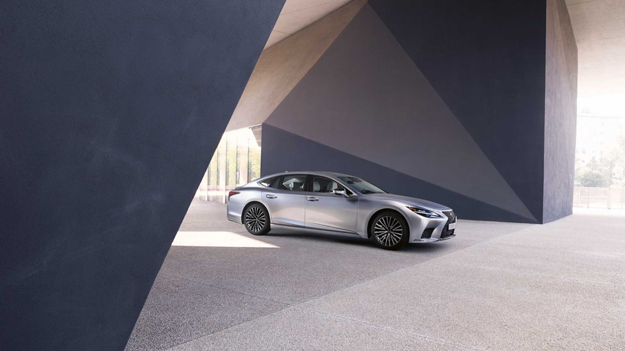 A Lexus LS parked under an abstract building