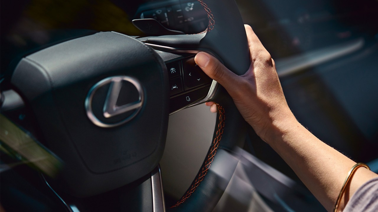 A hand placed on a Lexus steering wheel